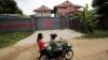 Women ride a motorcycle past a house that is used to temporarily house asylum seekers sent from a Nauru detention center in Phnom Penh, Cambodia, Aug. 31, 2015.
