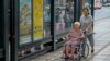 FILE - Caregiver pushes elderly wheelchair-bound woman through Taipei, Taiwan, Sept. 30, 2013.