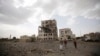 People stand by a building destroyed by a Saudi-led airstrike in Sana'a, Yemen, July 6, 2015. 