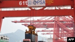 在中国东部江苏省连云港市的连云港港口，一台起重机将一个集装箱装上卡车（2021年9月7日）。