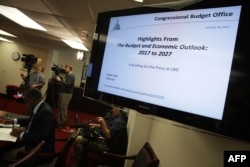 FILE - Members of the press cover a Congressional Budget Office (CBO) media briefing in Washington, D.C., Jan. 24, 2017.