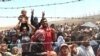FILE - Syrian refugees gather at the Turkish border as they flee intense fighting in northern Syria between Kurdish fighters and Islamic State militants in Akcakale, southeastern Turkey, June 15, 2015.