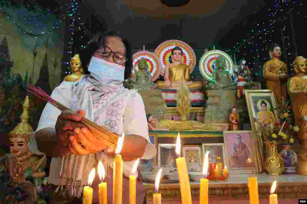 ស្រ្តីម្នាក់កំពុងអុជធូបក្នុងវត្តនិរោធរង្សី រាជធានីភ្នំពេញ ក្នុងពេលប្រារព្ធពិធីបុណ្យចូលឆ្នាំខ្មែរថ្ងៃទី២ នៅថ្ងៃទី១៤ ខែមេសា ឆ្នាំ២០២០។ (កាន់ វិច្ឆិកា/VOA)