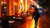 FILE - A woman passes empty tables before the late-night curfew due to restrictions against the spread of COVID-19 takes effect, in Berlin, Germany, Oct. 14, 2020.