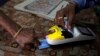 FILE - A woman places her finger on a biometric card reader before buying her quota of subsidized rice from a fair price shop under the Public Distribution System in Rayagada, in the Indian eastern state of Orissa, March 20, 2012.