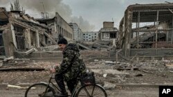 A man rides on a bike in front of the mail office which was destroyed by a Russian airstrike in Kurakhove, Donetsk region, Ukraine, Nov. 7, 2024. 