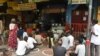 FILE - People in need sit while maintaining social distancing following COVID-19 Coronavirus guidelines, in front of a restaurant offering free meals in Ahmedabad, Sept. 19, 2020. 