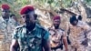 Le lieutenant général John Tshibangu, à l’avant-plan, entouré d’hommes armés en tenues militaires, à côté de véhicules 4x4, scandant des slogans pour un groupe appelé Forces nouvelles du Congo, dans des vidéos postées sur les réseaux sociaux, 18 janvier 2018. 