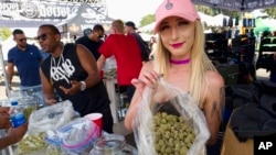 FILE - In this April 21, 2018, photo, a bud tender offers attendees the latest products of cannabis at the High Times 420 SoCal Cannabis Cup in San Bernardino, Calif.