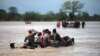 Flood-affected people cross a street on a boat in the aftermath of Hurricane Eta in La Lima, Honduras, Nov. 7, 2020.