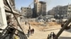 Palestinianos passam por edifícios danificados e destruídos em Beit Lahia, no norte da Faixa de Gaza, a 26 de outubro de 2024.