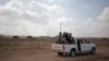 FILE - Palestinian Hamas gunmen ride on the back of a truck as they patrol the border with Israel near the southern Gaza Strip town of Khan Younis, as Israeli military bulldozers are seen in the background, June 10, 2015.