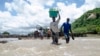 FILE - People cross a river with their belongings where a bridge once stood in Phaloni, Southern Malawi, Jan 22, 2015. 