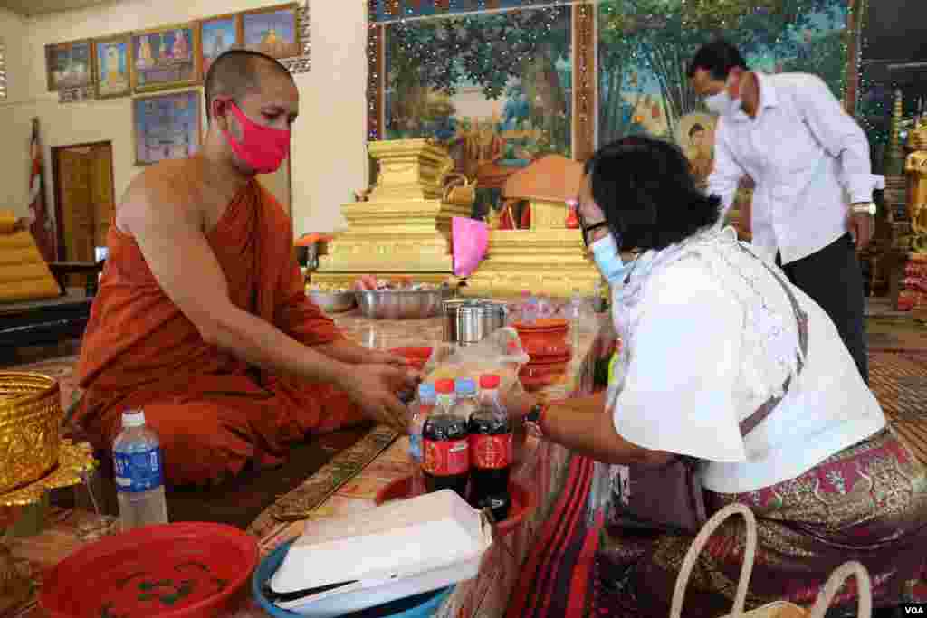 ស្រ្តីម្នាក់កំពុងប្រគេនទេយ្យទានដល់ព្រះសង្ឃក្នុងវត្តនិរោធរង្សី រាជធានីភ្នំពេញ ក្នុងអំឡុងពេលប្រារព្ធពិធីបុណ្យចូលឆ្នាំខ្មែរថ្ងៃទី២ នៅថ្ងៃទី១៤ ខែមេសា ឆ្នាំ២០២០។ (កាន់ វិច្ឆិកា/VOA)