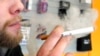 FILE - A sales associate demonstrates the use of an electronic cigarette and the smokelike vapor that comes from it in Aurora, Colo., March 2, 2011.