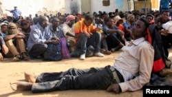 FILE - Illegal immigrants who were abandoned by traffickers in a remote desert area wait inside a military base in Dongola town, after being located by Sudanese and Libyan forces, May 3, 2014. 