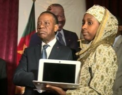 FILE - Cameroon's higher education minister, Jacques Fame Ndongo, hands a laptop to a female student, in Yaounde, Cameroon, Dec. 27, 2017. (M. Kindzeka/VOA)