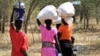 FILE - Women and girls walk back after getting food in Bentiu, a 38 kilometers (24 miles) journey using a path through the bush for fear of being attacked on the main road, near Nhialdu in South Sudan, Dec. 7, 2018,.