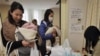Ibu-ibu dengan anak balita mendapat air minum dalam kemasan di sebuah klinik di Tokyo, Kamis (24/3).