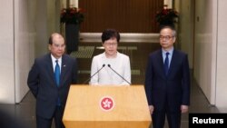 香港特首林鄭月娥在記者會上講話時，署理行政長官張建宗（左）和民政事務局局長劉江華（右）站在她身旁。（2019年9月5日）
