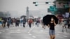 A woman wearing a mask walks past members of conservative civic groups who take part in an anti-government protest, as concerns over a fresh wave of the coronavirus disease (COVID-19) cases grow, in central Seoul