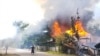 This handout taken on September 10, 2021 and received courtesy of an anonymous source on September 18 shows people attempting to extinguish a fire as houses burn in Namg Kar village in Magwe region's Gangaw township.