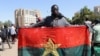 Un homme tient son drapeau national pour montrer son soutien à l'armée après l'arrestation du président burkinabé Roch Kaboré dans un camp militaire à Ouagadougou, Burkina Faso, le 24 janvier 2022.