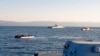 Un canot pneumatique avec des migrants, à gauche, dans l'étroite étendue d'eau entre l'île grecque de Lesbos et la côte turque, vendredi 2 avril 2021.