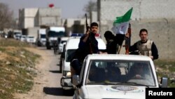 FILE - Free Syrian Army fighters head a convoy of vehicles carrying humanitarian supplies as they enter Damascus, March 20, 2014.