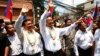 FILE PHOTO - Cambodia's opposition leader Sam Rainsy, center, of the Cambodia National Rescue Party waves along with his party Vice President Kem Sokha, third from left, during a march in Phnom Penh, Cambodia, Sunday, March 30, 2014. 