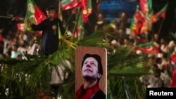 A supporter of Imran Khan, a Pakistani cricketer-turned-politician and chairman of the Pakistan Tehreek-e-Insaf (PTI) political party, holds up a cricket bat with an image of Khan during a rally on the last day of the election campaign in Islamabad May 9,