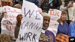 FILE - US citizens hold signs appealing for jobs as they attend a Democratic news conference about extending unemployment insurance benefits which expired Dec. 28, on Capitol Hill in Washington.