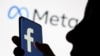 A woman holds a smartphone with the Facebook logo in front of a display of Facebook's new rebrand logo Meta in this illustration picture taken Oct. 28, 2021.