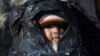 A child is covered in plastic as migrants travel by dinghy to the Greek island of Chios, from the Turkish coast near Cesme, Izmir, Turkey, Nov. 4, 2015. More than 300,000 people have traveled on dinghies and boats from nearby Turkey to Greek islands this 