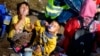 FILE - Children are seen eating milk powder as they wait for a bus in a temporary holding center for migrants near the border between Serbia and Hungary in Roszke, southern Hungary, Sept. 13, 2015.