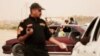 An Iraqi counterterror officer talks to people in a convoy of families fleeing Islamic State-held Hit, Iraq, at a checkpoint on the western edge of Ramadi, Iraq, March 20, 2016.
