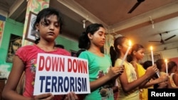 Des élèves en prière de solidarité avec les victimes d'une attaque djihadiste, tiennent des bougies et une plaque dénonçant le terrorisme, à Dhaka, au Bangladesh, 3 juillet 2016. REUTERS / Jayanta Dey 