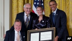 President Barack Obama, right, with former President George H. W. Bush, left, present the 5,000th Daily Point of Light Award to Floyd Hammer and Kathy Hamilton, center, from Union, Iowa, in the East Room of the White House, Jul. 15, 2013.