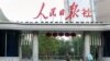 FILE - A man holding a smartphone walks past the headquarters of the Chinese Communist Party newspaper People's Daily, in Beijing, China, Oct. 6, 2018. 