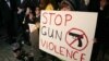 Sophie Bell, 9, holds a sign during an interfaith candlelight prayer vigil to end gun violence in front of Los Angeles City Hall in Los Angeles, California, December 19, 2012.