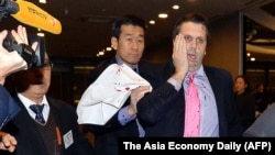 U.S. ambassador to South Korea Mark Lippert, right, covers a slash on his face as he leaves the Sejong Cultural Institute in Seoul, after he was attacked by an armed assailant, in Seoul, March 5, 2015.
