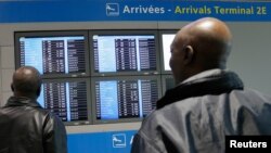 Des hommes regardent un écran d'information sur le vol AF755 d'Air France au départ de Conakry le 18 octobre 2014. REUTERS / Gonzalo Fuentes 