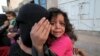 FILE - A girl cries next to her mother covering her face as they flee from an airstrike on an army weapons depot in Yemen's capital Sanaa.