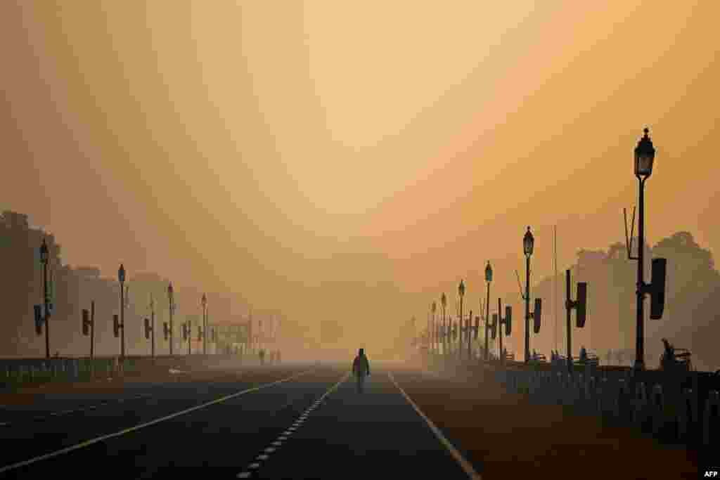 Seorang pria berjalan di sepanjang boulevard "Rajpath" di tengah kondisi berkabut akibat polusi udara di New Delhi, India, 28 Januari 2021. New Delhi adalah salah satu kota besar dunia dengan kualitas udara terburuk. (Foto: Jewel Samad / AFP)