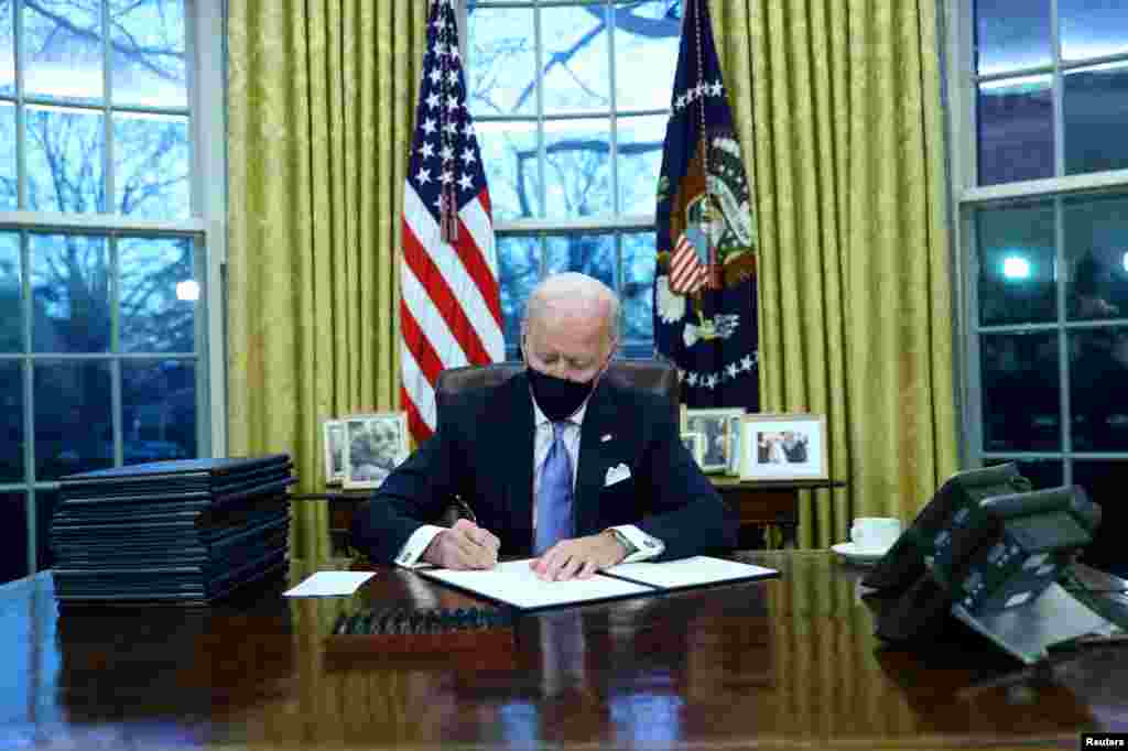 Presiden AS Joe Biden menandatangani beberapa perintah eksekutif (Keppres) di Ruang Oval Gedung Putih di Washington DC, setelah dilantik sebagai Presiden AS ke-46, 20 Januari 2021. (Foto: Reuters / Tom Brenner)