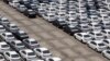 FILE - A man walks among cars which are ready for export at the port of Taipei, northern Taiwan, April 16, 2014. 