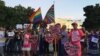 Vigil attendees hold signs against gun violence and homophobia, June 12, 2016. (K. Gypson/VOA)