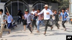 Cambodian garment workers run as they escape for safety in front of a factory of Yak Jin in Kambol village on the outskirts of Phnom Penh, Cambodia, Thursday, Jan. 2, 2014.