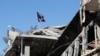 FILE - A flag of Islamic State militants is pictured above a destroyed house in Raqqa, Syria, Oct. 18, 2017. U.S. authorities have charged an American woman with aiding the Islamic State terror group.