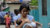 Une sri-lankaise s'éloigne du sanctuaire de St. Anthony, tenant son bébé après que la police a découvert des engins explosifs dans un véhicule garé à Colombo, au Sri Lanka, le lundi 22 avril 2019.
